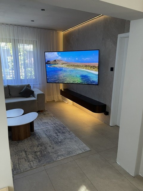 Fertig gestalteter Wohnbereich mit Fernseher und beleuchteter TV-Wand